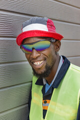 african worker with a big smile and a gold tooth wearing sunglasses and a hat