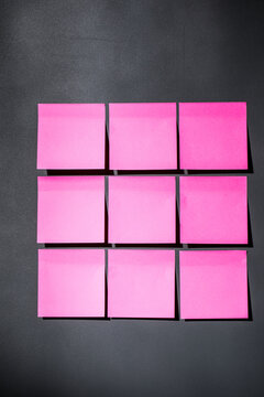 Pink sticky notes on dark gray magnet board