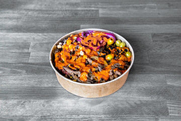 A flavorful beef salad bowl topped with olives and drizzled with spicy sauce. Perfect for healthy eating and vibrant culinary presentations.