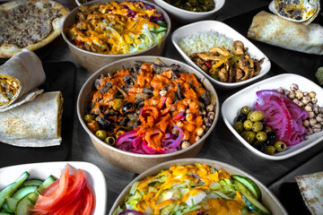 An overhead shot of assorted Mediterranean dishes including vibrant wraps, fresh salads, and a variety of sides, capturing the rich colors and textures of Mediterranean cuisine.