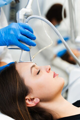 Cosmetologist removes wrinkles and scars using laser from face of attractive girl. Process of...