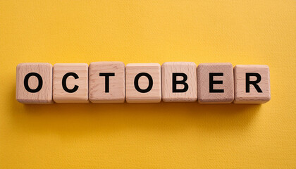 Wooden cubes with text OCTOBER on yellow backdrop. Autumn season. Month of year. Close-up. Flat lay