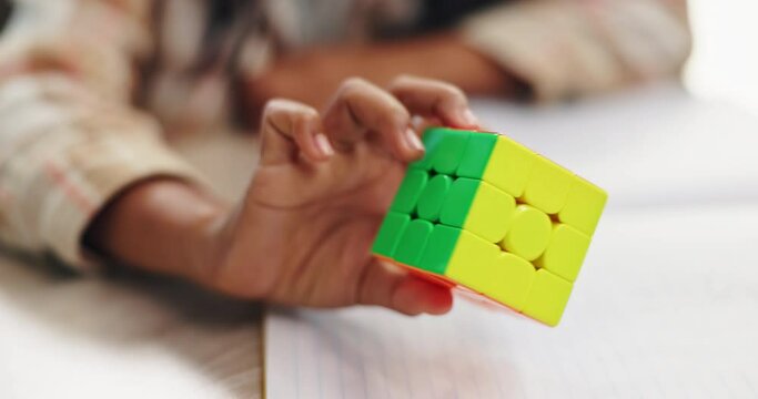 Color, cube and puzzle on hands, challenge and closeup of student in classroom with notebook and desk. Middle school, growth and development of child with game of pattern, solving and goal for kid