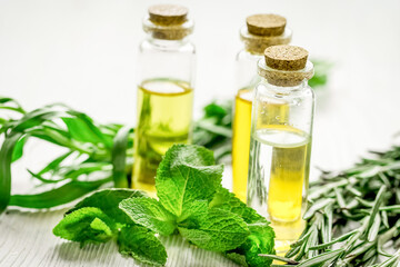 natural cosmetic oil with fresh rosemary and mint on light wooden table background