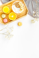 granola with banana slices, macaroons and orange juice for breakfast on blue background top view copyspace