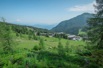 Naklejka premium Nassfeld ski slope in summer. Visible lower ski lift station overlooking green meadows under the blue sky. Alpine panorama in summer