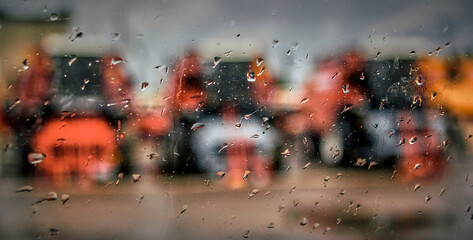 View from the window on a rainy day of combine harvesters parked in the parking lot