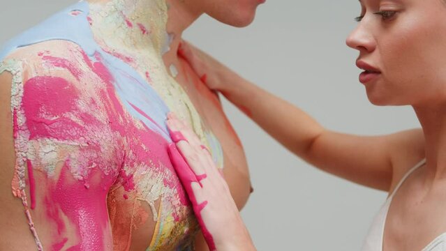 Young couple man and woman doing body art with colourful paints on each other .Man and woman drawing colours paint on their bodies. Body art therapy with many various of paints. Painting on human body