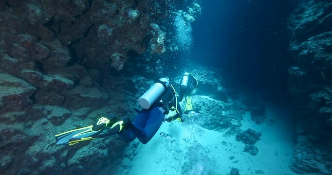 Group of divers swimming in an underwater cave canyon. Diving instructor and group students in underwater exploration. The instructor teaches the students. Scuba diving training and education.