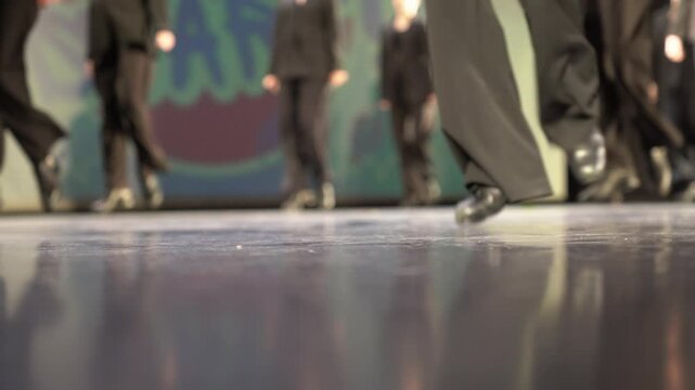 Women's legs in trousers and black shoes. In a stage costume, they tap dance on a hard floor illuminated by light. A light kick. Selective focus. High quality 4k footage