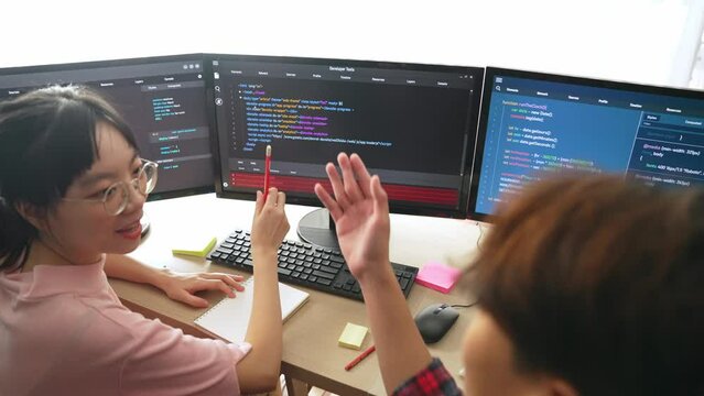 Slow motion back end software developer engineer for computer programming working together on debugging writing computing code, solving complex algorithms display on monitor in office. Burgeoning