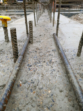 Construction joint preparation and concrete scabbling with steel reinforcement bars embedded in concrete on a construction site. Close-up view of concrete with laitance removed.