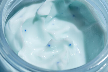 Liquid cream cosmetic smudge blue micro capsules microsphere texture in glass jar macro close up