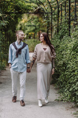 Fototapeta premium Copy space. overs are laughing. Happy guy and girl. Lovers enjoy each other in the evening park. Happy romantic moments of lovely couple in park during dating. Girl with tattoos.