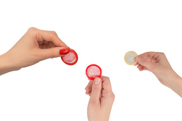 A red condom in a woman hand with red nails isolated on white background.