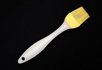 A basting brush with silicone bristles on black fabric.