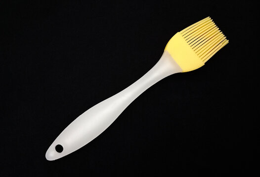 A basting brush with silicone bristles on black fabric.