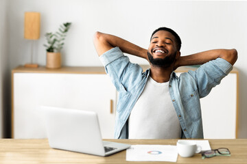 Life is good. Cheerful african american employee sitting on chair with hands behind his head,...