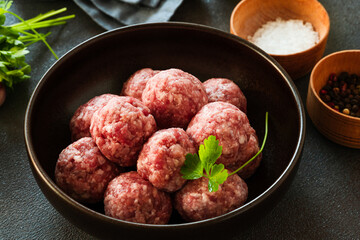 Raw ground beef meatballs in black bowl