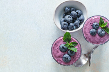 Healthy blueberry smoothie in glass on lighgt blue background