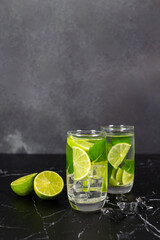Mojito cocktail with lime, mint and ice on the black marble, dark background. Sparkling refreshing water. Space for text.  