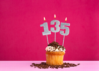 Birthday celebration with candle number 135 - Chocolate cupcake on pink background