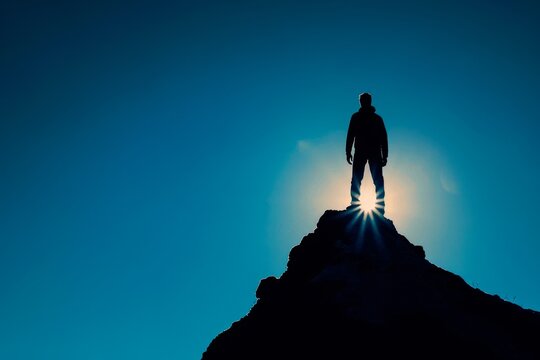 Silhouette of a person standing on top of a mountain, symbolizing success and achievement concept