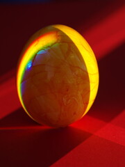 A small, yellow egg is sitting on a red surface