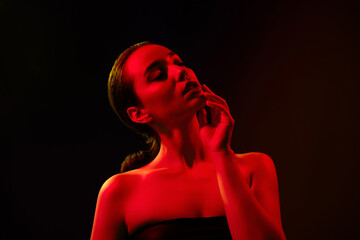 Photo of charming attractive lady nude shoulders seducing touching chin isolated black orange neon...
