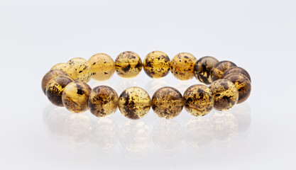 Bracelet made of Natural polished transparent honey luxury amber beads on white background. close up selective soft focus. 