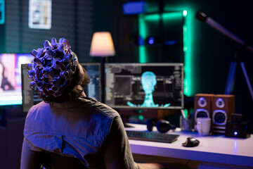 Computer technician entering trance, wearing EEG headset on head to communicate with artificial intelligence entity. IT admin using high tech gear to link mind with AI robot, gaining superintelligence