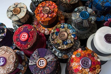 A collection of button-adorned hats, each a masterpiece of millinery