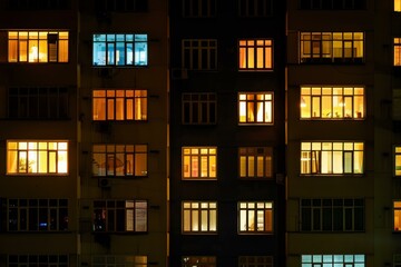 Windows illuminating apartments at night showing that people are home relaxing