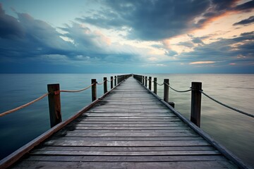 Obraz premium Wooden pier extending into a calm sea with a dramatic cloudy sky at dusk