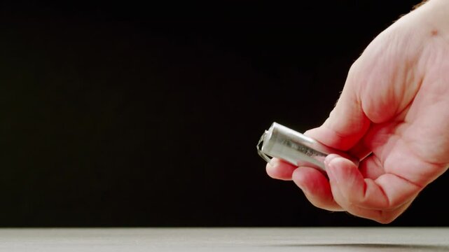 Silver batteries AA and AAA in hands on black background close-up. Double-A battery is a standard size single cell cylindrical dry battery. Batteries are common in portable electronic devices. An AA