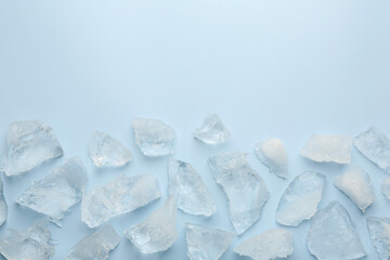 Pieces of crushed ice on light blue background, top view. Space for text