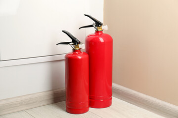 Obraz premium Fire extinguishers on floor near beige wall indoors
