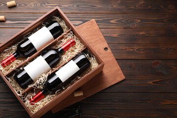 Box with wine bottles on wooden table, top view. Space for text