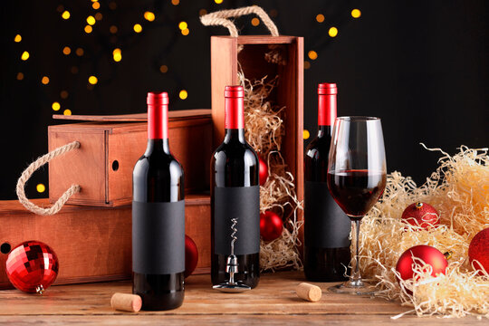 Bottles of wine, glass, wooden boxes, corks and red Christmas balls on table
