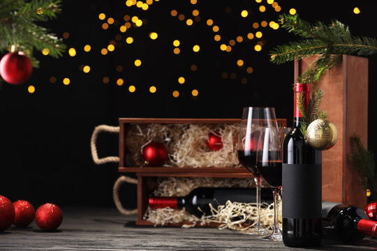Bottles of wine, glasses, wooden boxes, fir twigs and Christmas balls on table