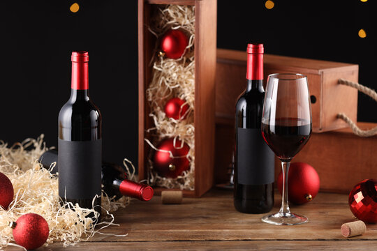 Bottles of wine, glass, wooden boxes, corks and red Christmas balls on table