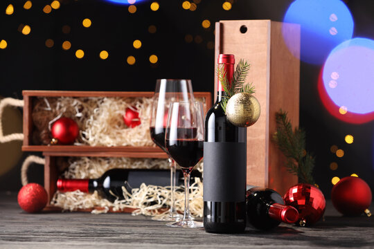 Bottles of wine, glasses, wooden boxes, fir twigs and Christmas balls on table