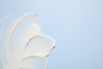 Face cream on light blue background, top view. Space for text