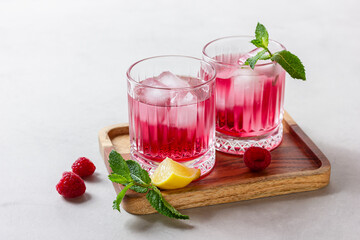 Raspberry cocktail with ice in a glass on a light background