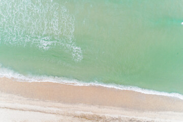 waves on the shore of a turquoise waters beach in the summer, aerial overhead view with drone