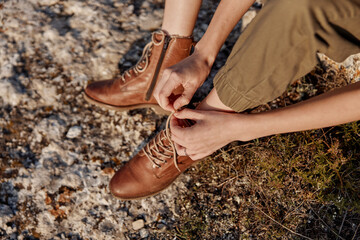 Tying shoes on rocky hillside with feet in air while traveling in a remote area