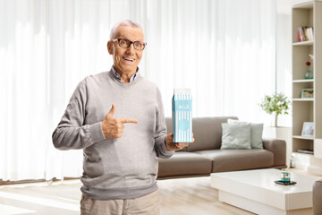 Elderly man holding a milk carton and pointing