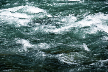Close-up of a river flow on the rocks. Clean bubbling transparent blue water in a mountain river. Selective focus.