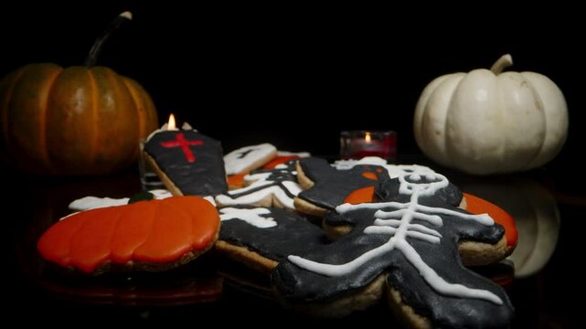 Halloween Cookies on a Black Table Emerging from the Darkness. Candles Burning in the Background with Mini Pumpkins.