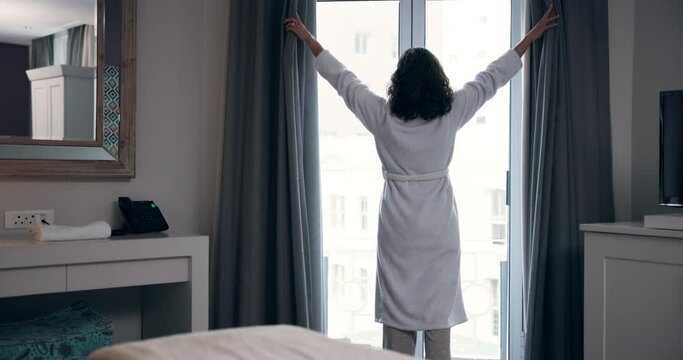 Back, woman and open curtain in hotel or bedroom for wake up, morning routine and fresh air in robe. Person, new day and drapes of window in home for daylight, getting ready and view of accommodation